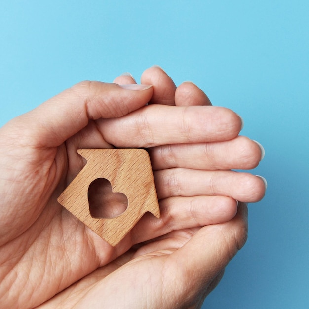 A wooden house in the hands of a man. A symbol of protection and care for home and family