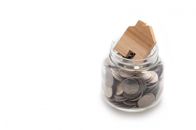 Wooden house modeled on many coins in a glass jar