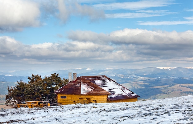 Wooden house on october Carpathian mountain plateau with first winter snow