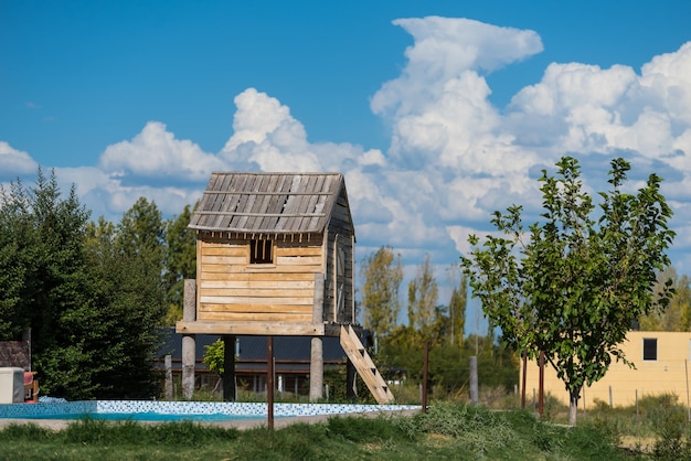 A wooden house with a pool in the background