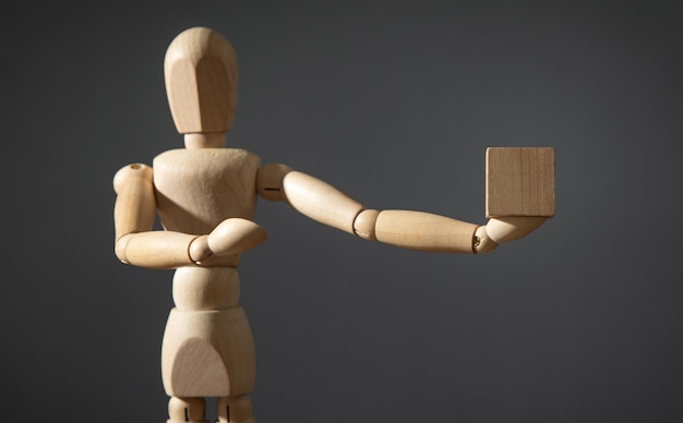 Wooden human figure holding wooden empty cube