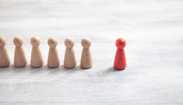 Photo wooden human figures on the white desk. leader