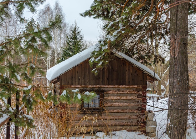 A wooden hut in the forest in winter under the snow.