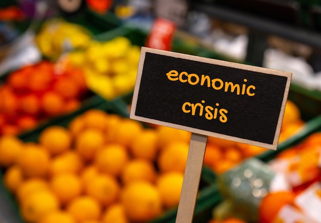 Wooden information label sign with text ECONOMIC CRISIS against defocused store shelves message