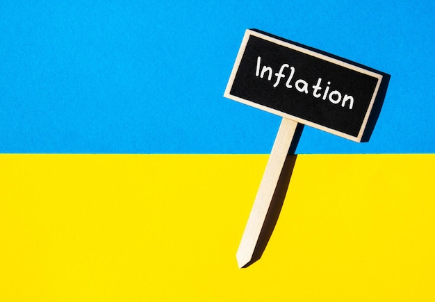 Wooden information label sign with text INFLATION against Ukrainian national flag message