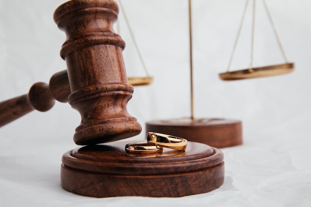 Wooden judge gavel with rings closeup on light background Family divorce and law concept