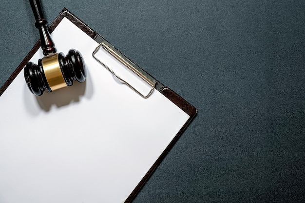 Photo wooden judgeâs gavel and paper clipboard on black leather background.