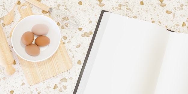 Photo wooden kitchen accessories for making cakes with a large blank book next to them and eggs inside a bowl