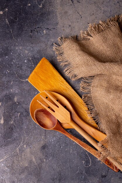 Wooden kitchen tools lie on a rough canvas napkin copy space