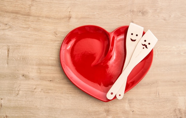 Wooden kitchen utensils on red hearth plate Funny food