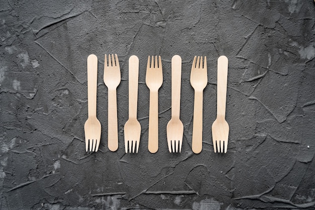 Wooden knife and fork on the black background. Eco friendly zero-waste concept. Top view with space for text. Copy space