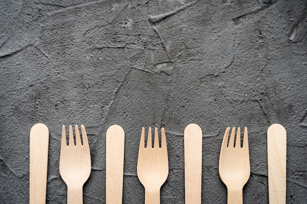 Wooden knife and fork on the black background. Eco friendly zero-waste concept. Top view with space for text. Copy space