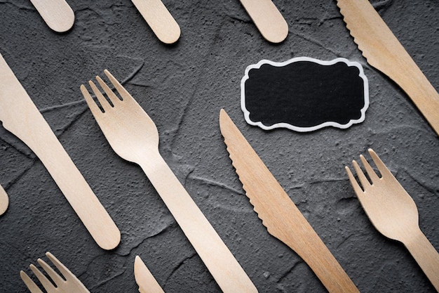 Wooden knife and fork on the black background Eco friendly zerowaste concept Top view with space for text Copy space