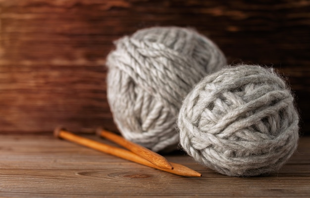 Wooden knitting needles with skeins of yarn on a wooden background.