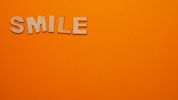 Wooden letters on plain colored background with the word written in English Smile