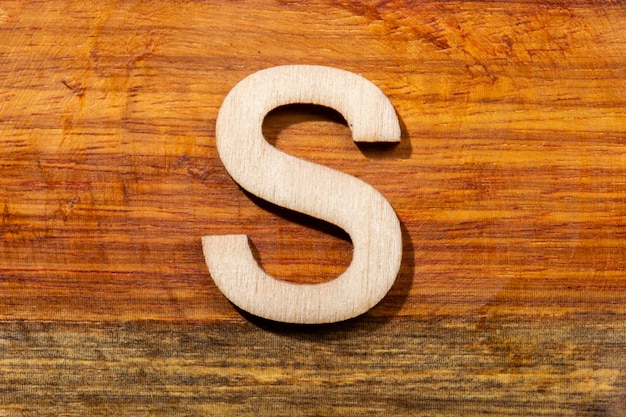 Wooden letters S on wooden background top view