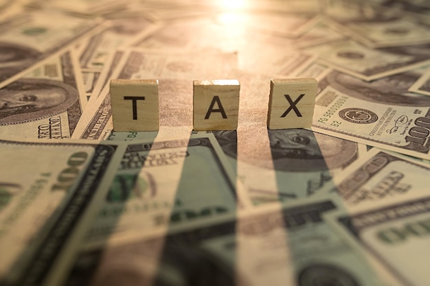 Wooden letters with the word tax On dollars with an illuminated background