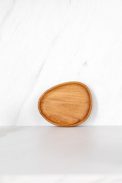 Wooden little oak dish board tray standing near the wall Empty wooden plate on kitchen white table