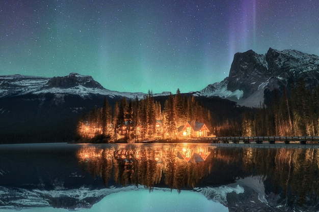 Wooden lodge illuminated with Aurora borealis on Emerald lake at Yoho national park