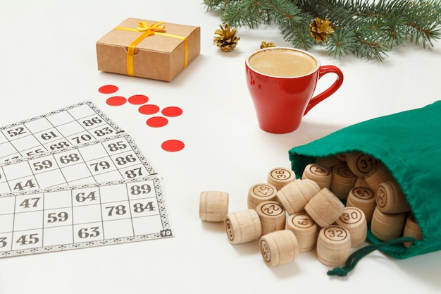 Wooden lotto barrels with bag game cards with cup of coffee and red chips for a game in lotto