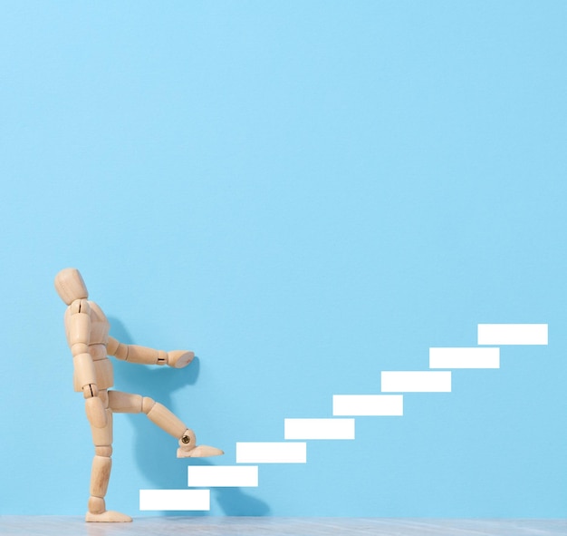 A wooden mannequin and drawn steps going up a concept of achieving a goal strong personality