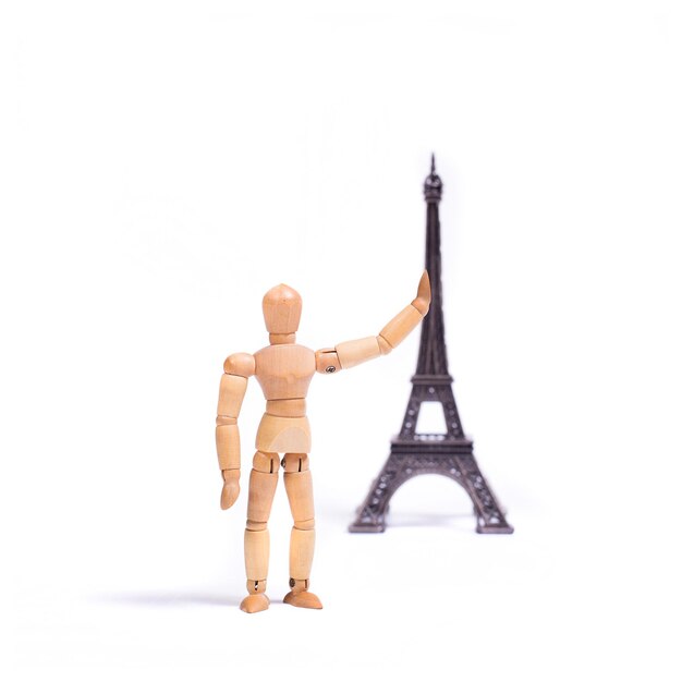 Photo a wooden mannequin is pointing at a eiffel tower.