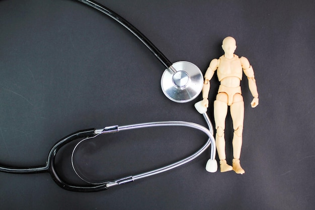 A wooden mannequin next to a stethoscope with a stethoscope on it.