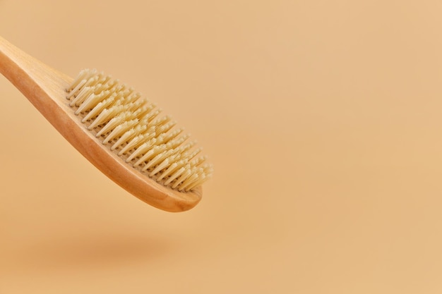 Wooden massage brush with natural bristles on beige background