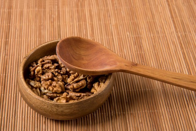 On a wooden mat walnuts in a wooden cup with a wooden spoon