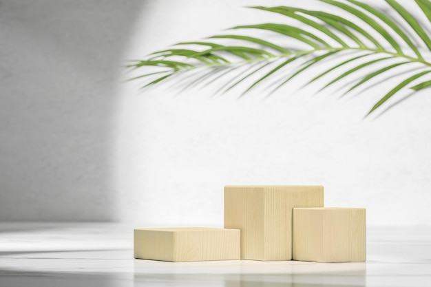 Wooden natural cube podium in white and grey marble interior with shadow Summer modern showcase with cube wooden podium with green palm leaf in sunlight shadow on grey marble wall