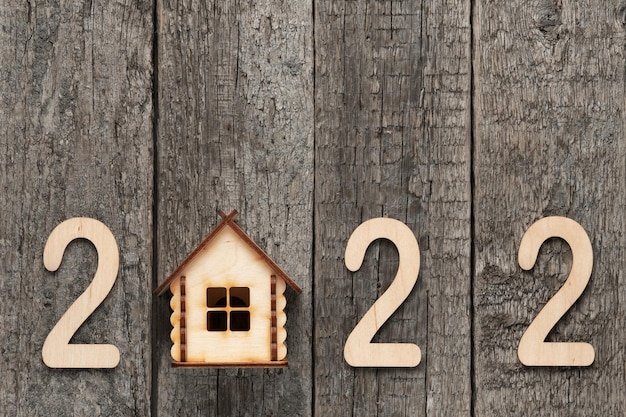 Wooden numbers 2022 and wooden country house on old wooden boards