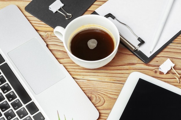 Wooden office desk table and equipment for working with black coffee in angle view