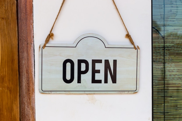 Wooden open signboard hanging on a door