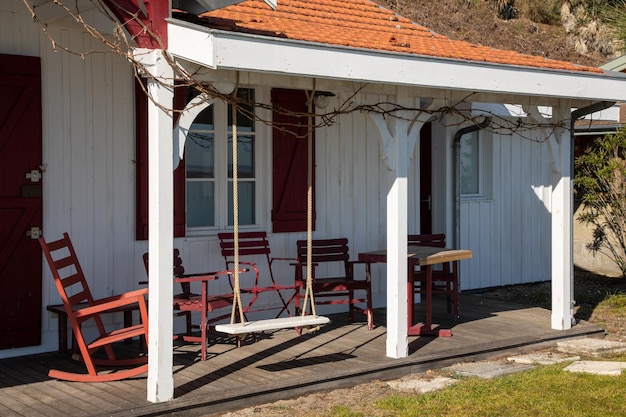 Wooden patio set including red table and chairs as well as a swing set on a wood deck in the sunny garden