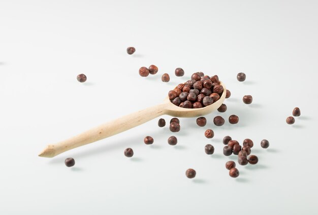 Wooden peasant spoon filled with dark pea seeds