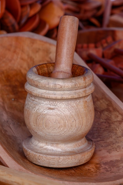 Wooden pestle in reddish tint amidst several handcrafted kitchen utensils