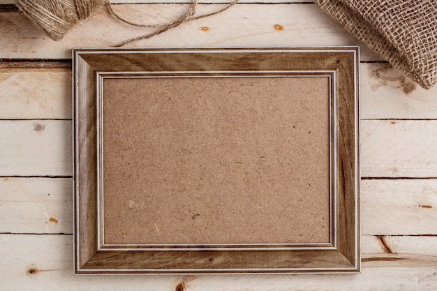 Wooden photo frame on light wooden background, top view, copysàce