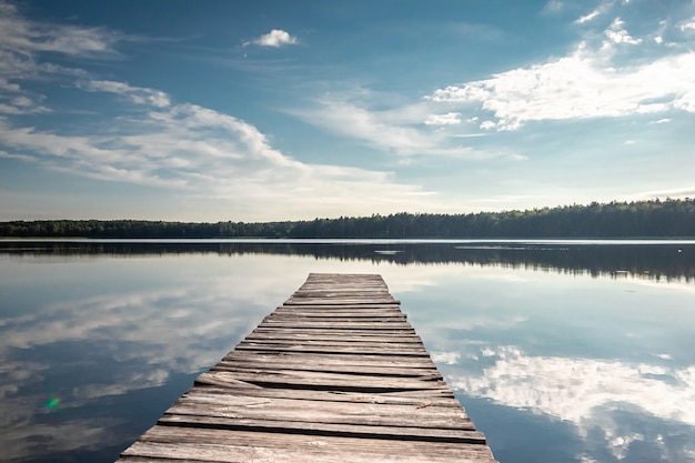 Wooden pier on beautiful lake summer dawn landscape. Copy space.