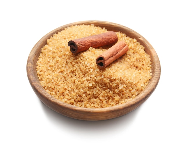 Wooden plate with cinnamon sugar and sticks on white background