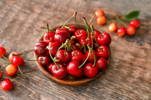 Wooden plate with fresh ripe cherries on table