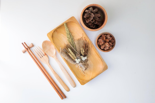 Wooden plate with wooden utensils on a white table