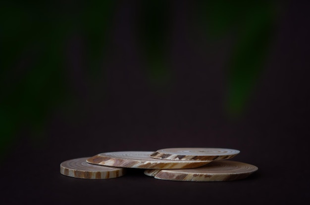 Wooden podium pedestal. Brown background dark green leaves