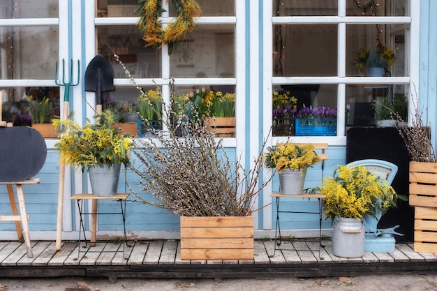 Wooden porch of house with plants. Facade home with garden tools and pots flowers.