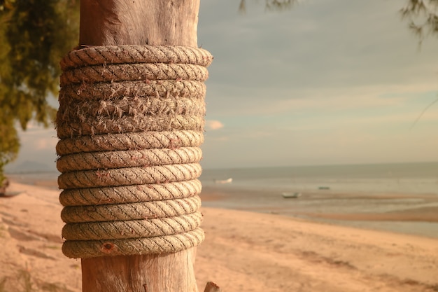 Wooden post with mooring ropes on the beach. 