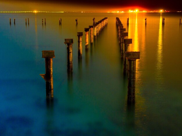 Photo wooden posts in lake against sky at sunset