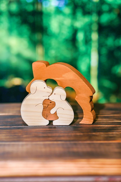 Wooden puzzle in the form of a family of handmade dogs on the background of the forest