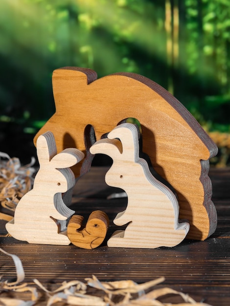 Wooden puzzle in the form of a family of handmade hares on the background of the forest