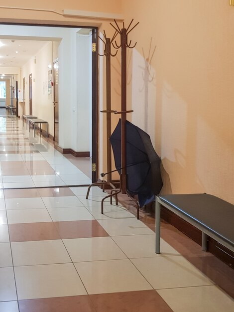 Wooden rack hanger with an open umbrella in an empty room of the corridor of a medical clinic, vertical.