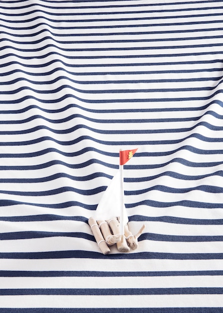 Wooden raft with a white sails on a sailor's shirt instead of the sea.