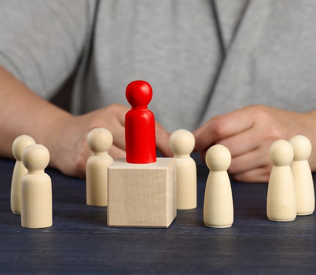 Wooden red figurine chosen from the crowd. The concept of finding talented employees, managers, career growth. Staff recruitment, close up